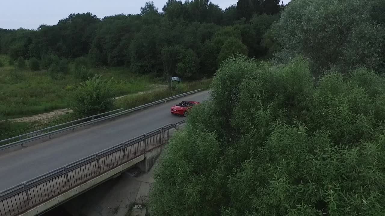 Czerwony kabriolet na moście w lesie