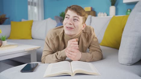 un joven en casa soñando despierto y riendo.