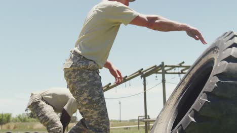 Passen-Sie-Eine-Vielfältige-Gruppe-Von-Soldaten-An,-Die-Traktorreifen-Auf-Einem-Armee-Hindernisparcours-In-Der-Sonne-Umdrehen