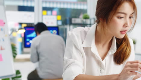 successful asian executive director young business woman in smart casual wear drawing writing, using belt with diverse professionals working on business statistics, marketing plans in corporate office