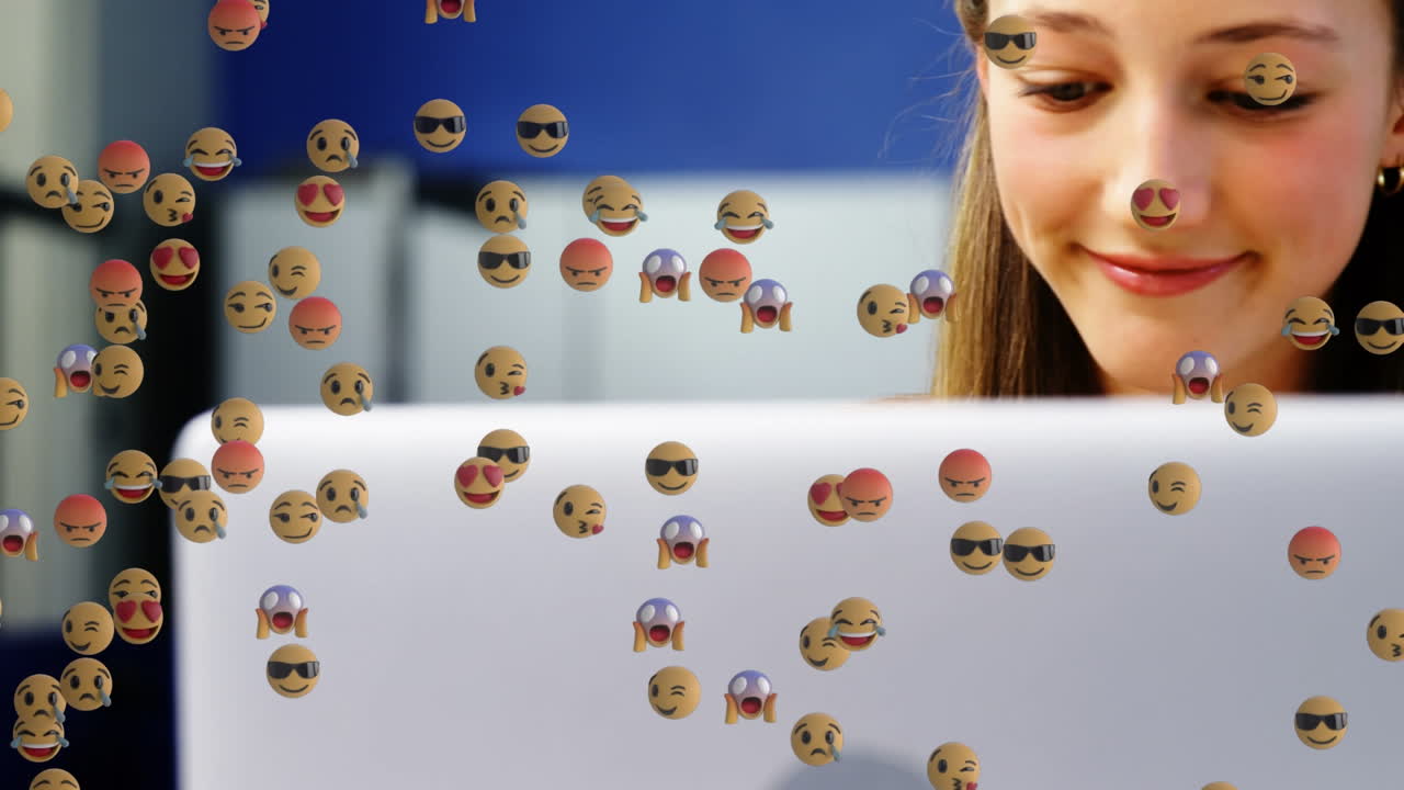 animación de emoticones sobre un niño y una niña caucásicos felices usando computadoras portátiles