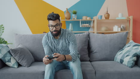 hombre jugando videojuegos en un sofá