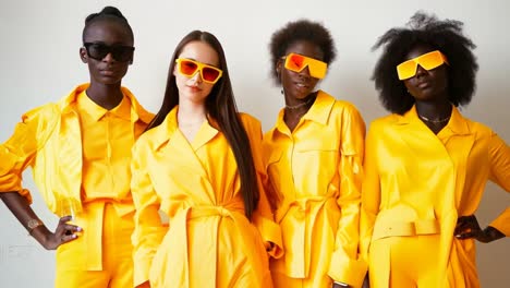 a group of four women in yellow outfits and sunglasses