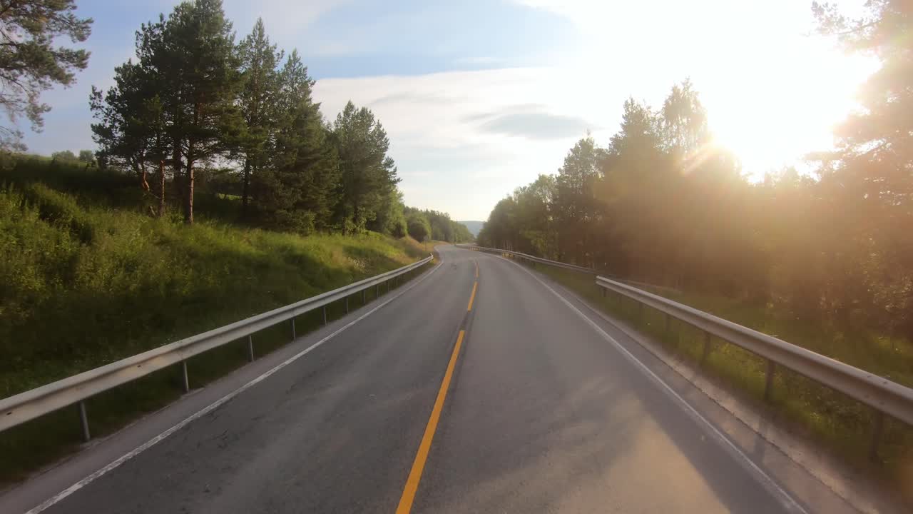 Guida di un'auto su una strada in Norvegia all'alba