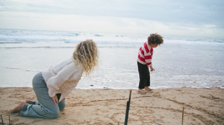 Lille dreng leger ved havets kyst med mor. Familie weekend på efterårsstrand.