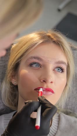 a woman is getting her lips done by a makeup artist - a woman getting makeup artist service for her lips