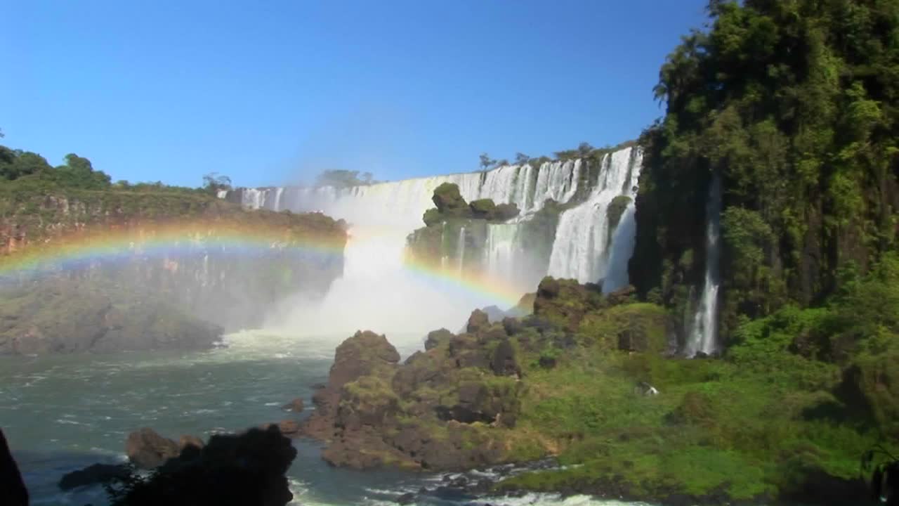 una hermosa toma amplia de las cataratas del iguazú con un arco iris en primer plano