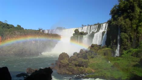 una hermosa toma amplia de las cataratas del iguazú con un arco iris en primer plano