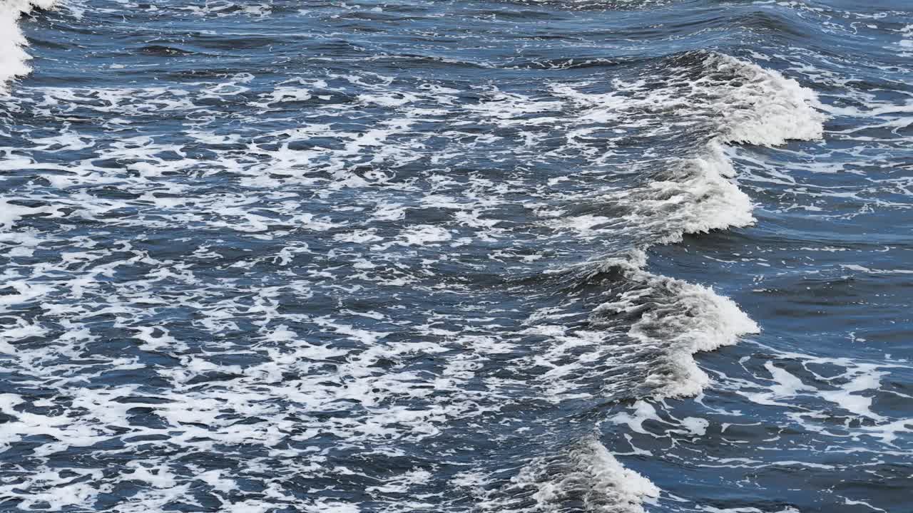 Aerial view of turbulent ocean waves with dynamic movement and natural lighting, creating a dramatic and immersive seascape