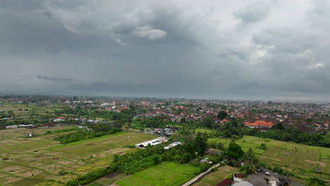 Campos-De-Arroz-Con-El-Centro-De-La-Ciudad-De-Bali-Al-Fondo,-Indonesia.