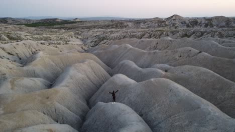 Rising-aerial-shot-of-an-athletic-young-person-standing-in-the-Mahoya-desert-of-Spain