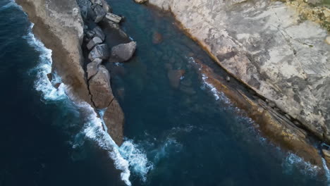 aerial view of sea waves splashing on rocky shore