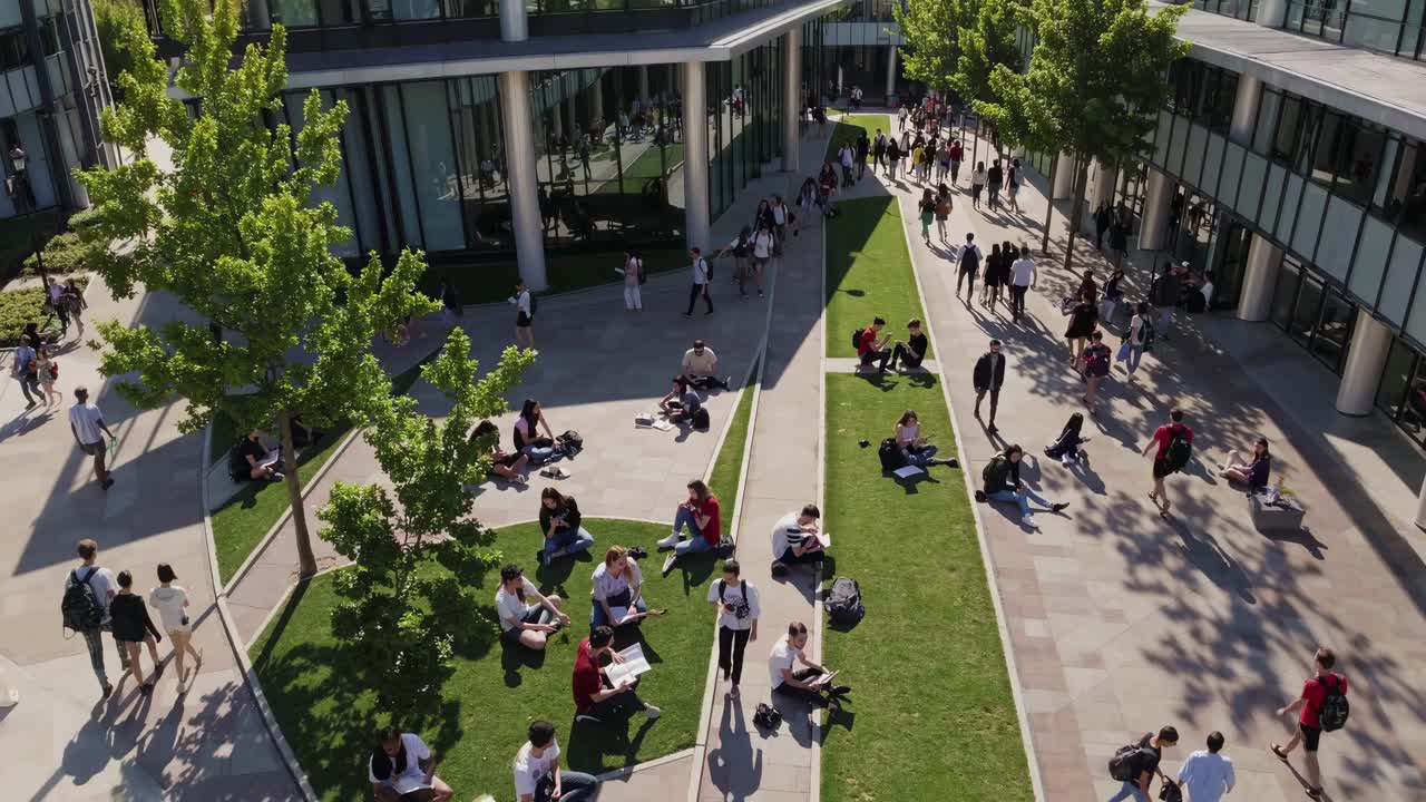 Aerial view of a modern campus with students relaxing on grass. The ...