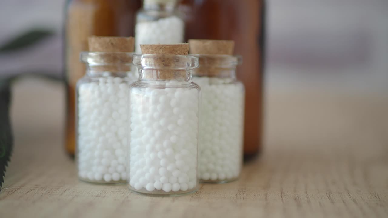 Small Glass Bottles Filled with White Homeopathic Globules