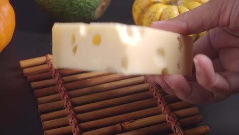 una mano sosteniendo un pedazo de queso suizo