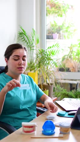 young female dentist displaying various dental models at her desk