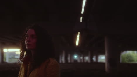 woman standing under an urban overpass at night