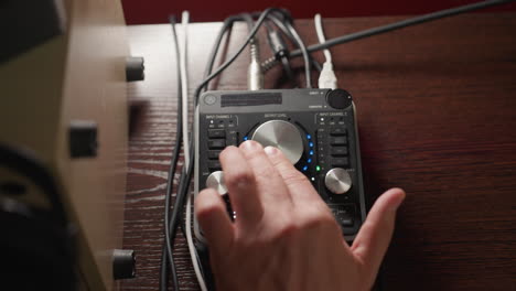 close-up of a hand operating a sound mixer, rotating a knob to adjust audio levels. precise work involved in sound engineering, with various cables connected to the mixer