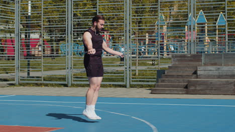 athletic lebanese man in sportswear skipping rope doing jumping exercises on basketball court