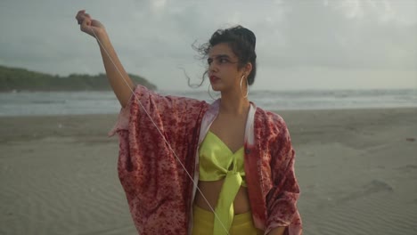 a beautifully captured view showcases a stunning asian model, gracefully gazing at a kite against the backdrop of a breathtaking beachside scenery