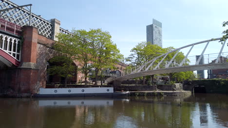 Statische-Aufnahme-Der-Skyline-Von-Manchester-Mit-Dem-Beetham-Tower-In-Der-Ferne-Und-Einem-Zug,-Der-An-Einer-Brücke-Im-Vordergrund-An-Einem-Sonnigen-Tag-Vorbeifährt