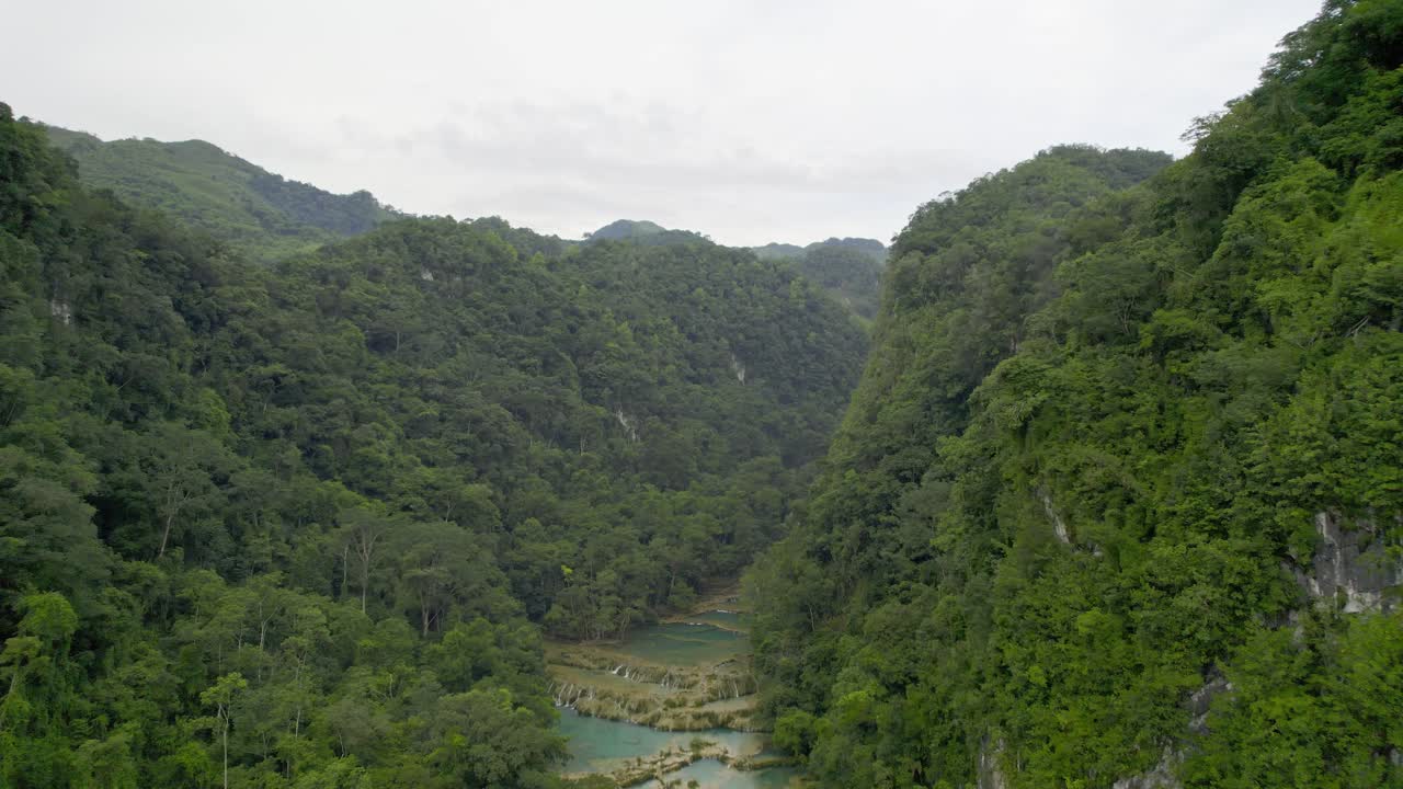 imágenes aéreas de drones del parque nacional semuc champey en guatemala rodeado de colinas y montañas de selva verde brillante en un día nublado