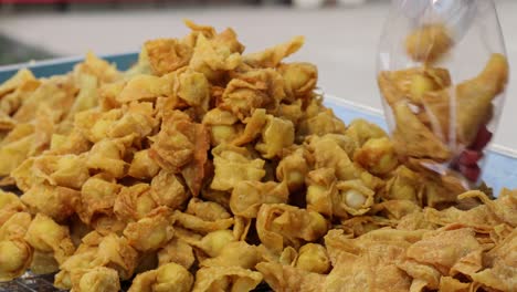 hands serving crispy fried snacks from a large tray