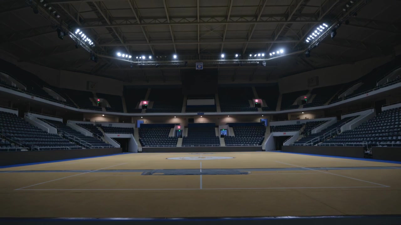 Luci a soffitto che si attenuano, trasformando il campo da gioco centrale vuoto dell'arena in un'illuminazione d'accento rosa tenue.