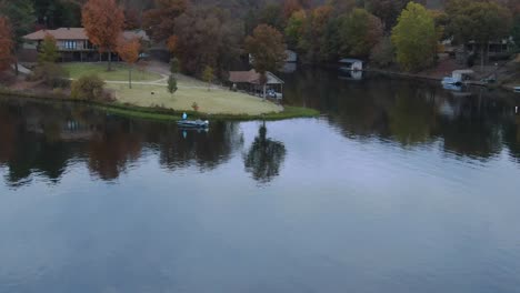 low altitude aerial view of bass fisherman in boat along shore of retirement community lake