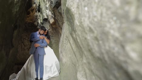 Groom-with-bride-standing-in-cave-of-mountain-hills.-Wedding-couple-in-love