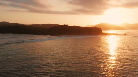 Sunrise-at-the-surf-spots-of-Gerupuk-in-Lombok,-with-a-view-on-the-bay-with-the-fishing-boats-and-surfers