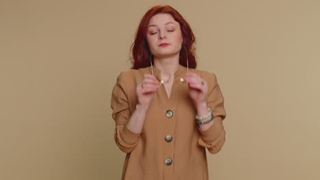 a woman with red hair smiles at the camera while wearing glasses and a brown shirt.