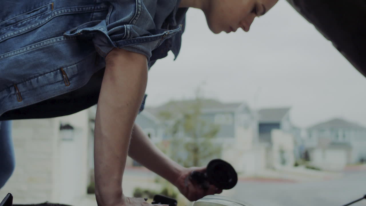 mujer de 20 años revisando debajo del capó de un camión y pasando debajo del camión para encontrar y solucionar problemas mecánicos