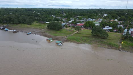 Vista-Aérea-Alejándose,-Vista-Panorámica-Del-Río-Amazonas-Con-Pequeños-Botes-Anclados-En-Un-Día-Nublado