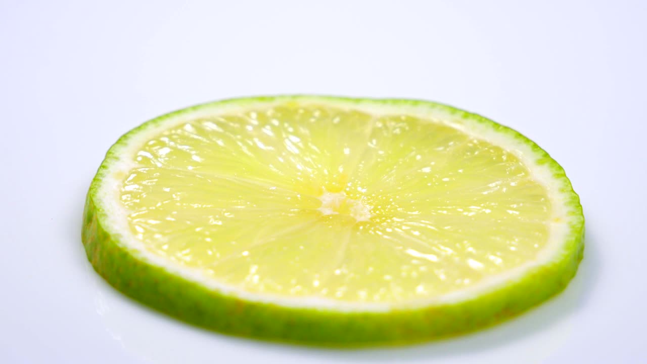 una rebanada de limón verde está girando lentamente en el estudio con los detalles.