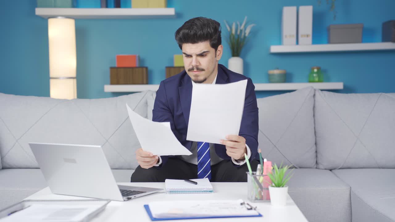 Uomo che esamina documenti è teso e stressato.