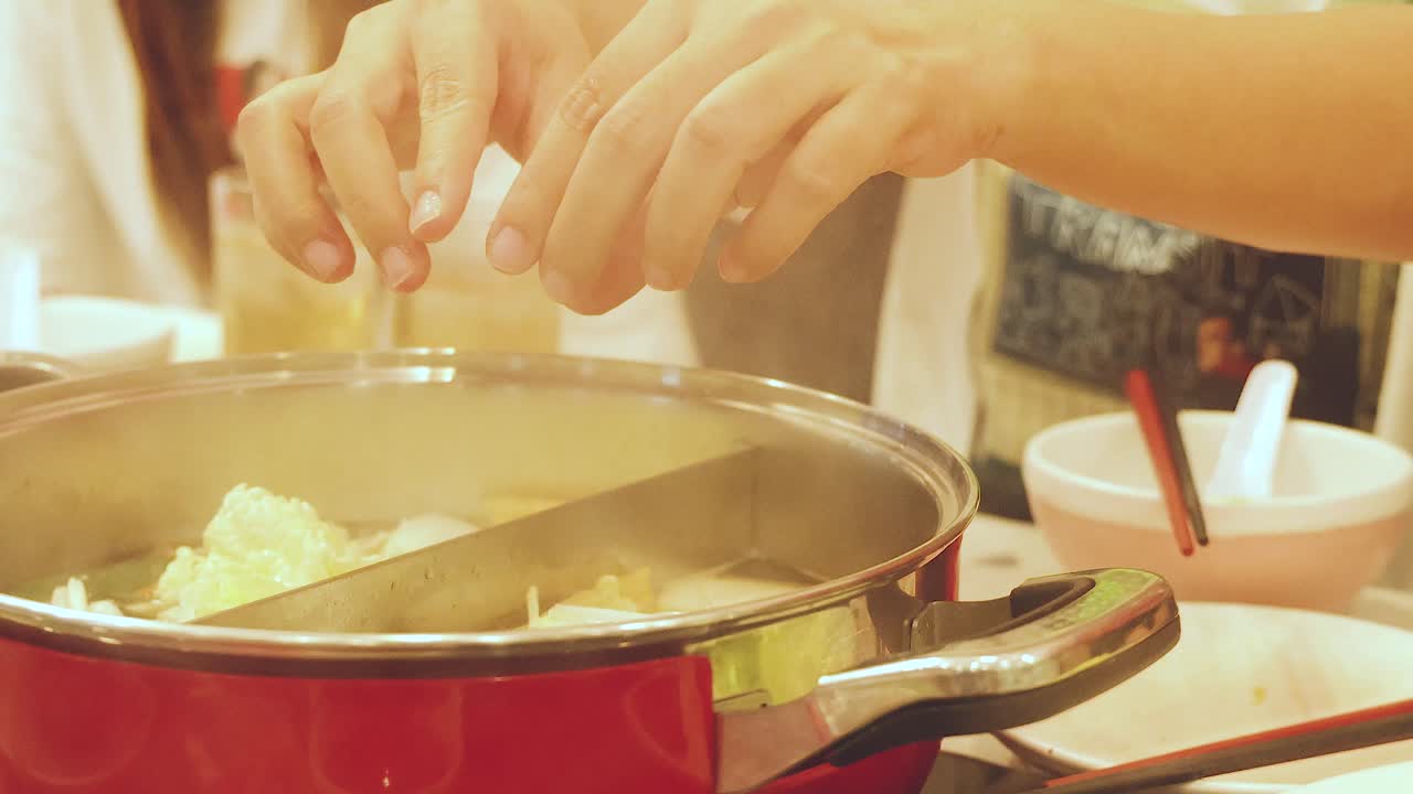 manos preparando una olla caliente con ingredientes frescos