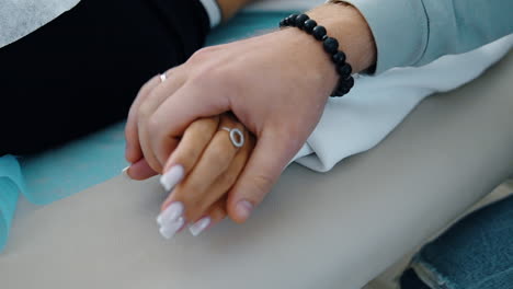 beautiful female hand lies on the hospital couch. male hand takes the female ones showing support. close up.