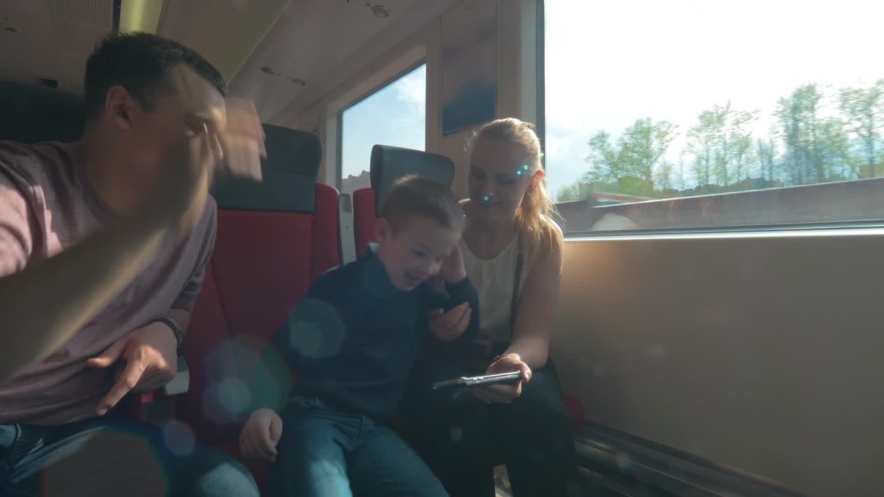 Genitori e bambino che viaggiano in treno e usano lo smartphone