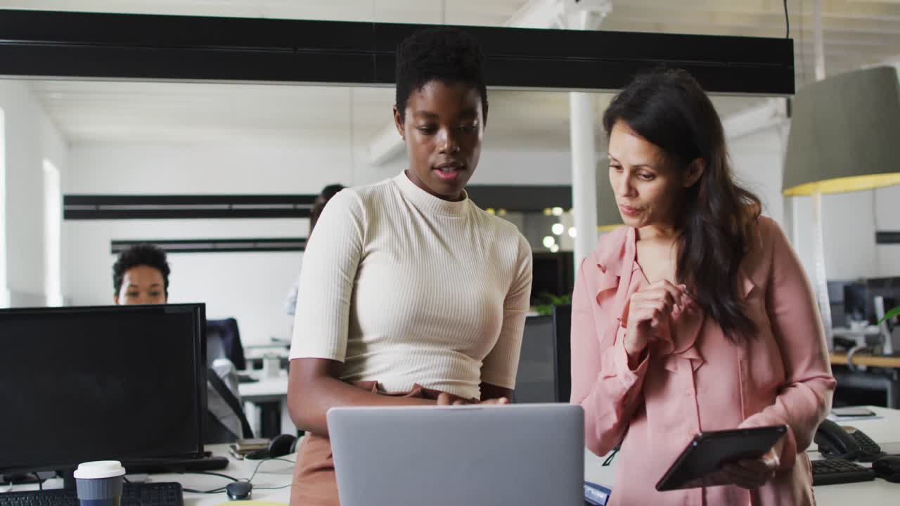 Focused diverse businesswomen working together on laptop in office