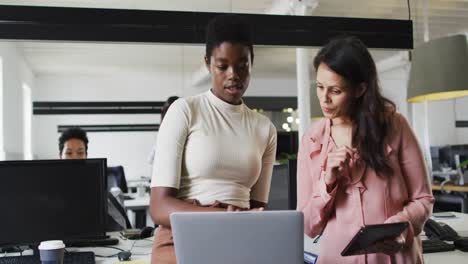 Focused-diverse-businesswomen-working-together-on-laptop-in-office