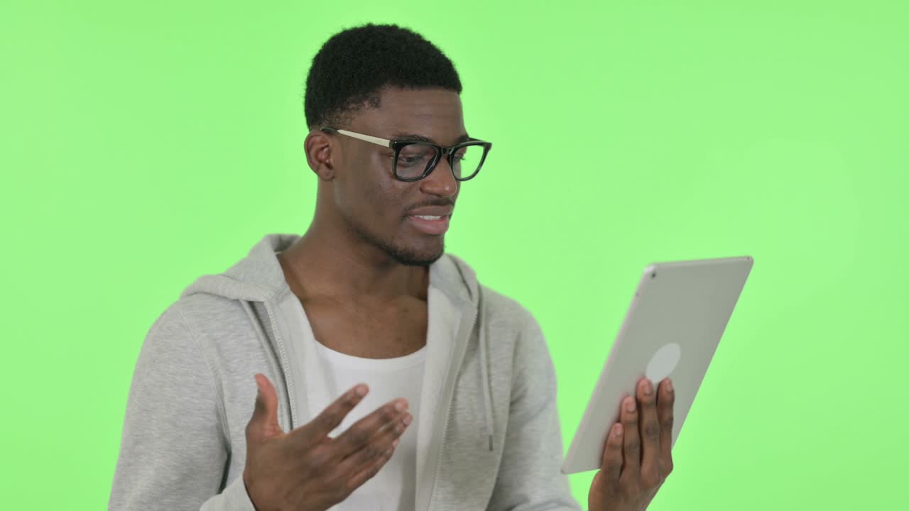 Video Chat on Tablet by African Man on Green Background