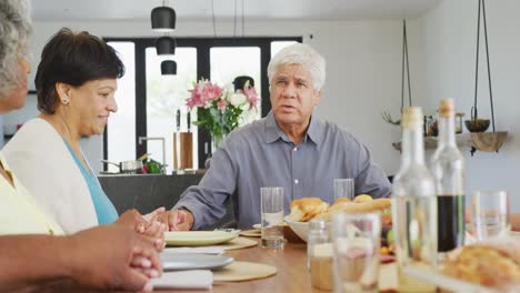 personas mayores felices y diversas orando antes de la cena en el hogar de ancianos