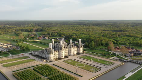 left panning pov chambord castle garden green surrounding forrest end of the day, works with scaffoldings