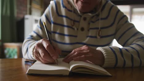 senior man writing in a book at home