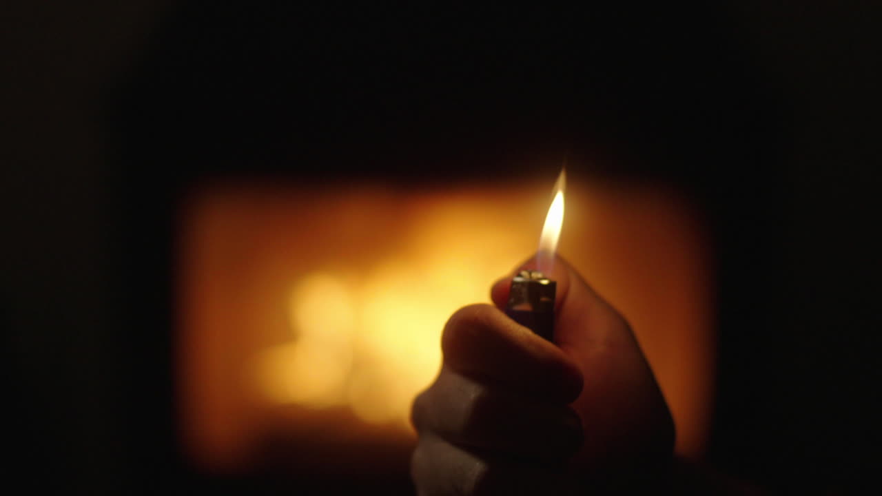 Hand holding a lighter near a fire
