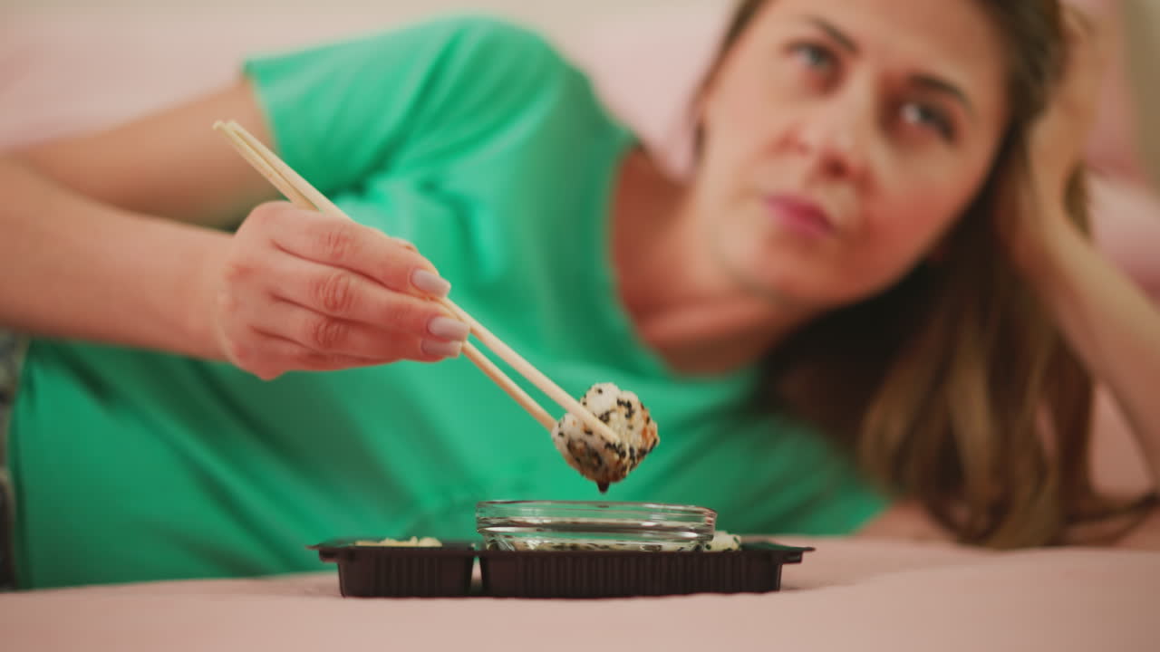 Woman eating sushi onigiri in bed