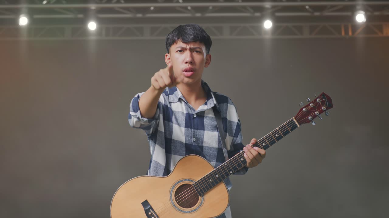 무대에 서 있는 동안 기타를 들고 카메라에 소리치는 아시아 십대