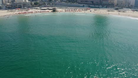 Schöne-Drohnenaufnahme-Des-Wassers,-Während-Sie-In-Richtung-Land-Fliegt,-Um-Die-Beliebte-Touristenattraktion-Des-Strandes-Von-Tel-Aviv-Zu-Enthüllen