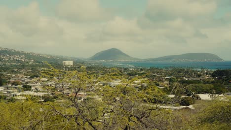 Toma-Panorámica-Desde-La-Costa-Hawaiana-Cerca-De-Diamond-Head-Hasta-La-Ciudad-Cercana-Desde-Un-Punto-De-Vista-En-La-Cima-De-Una-Montaña.